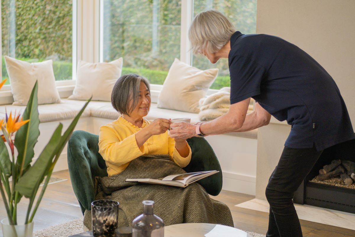 A support worker offers a woman a cup of tea.