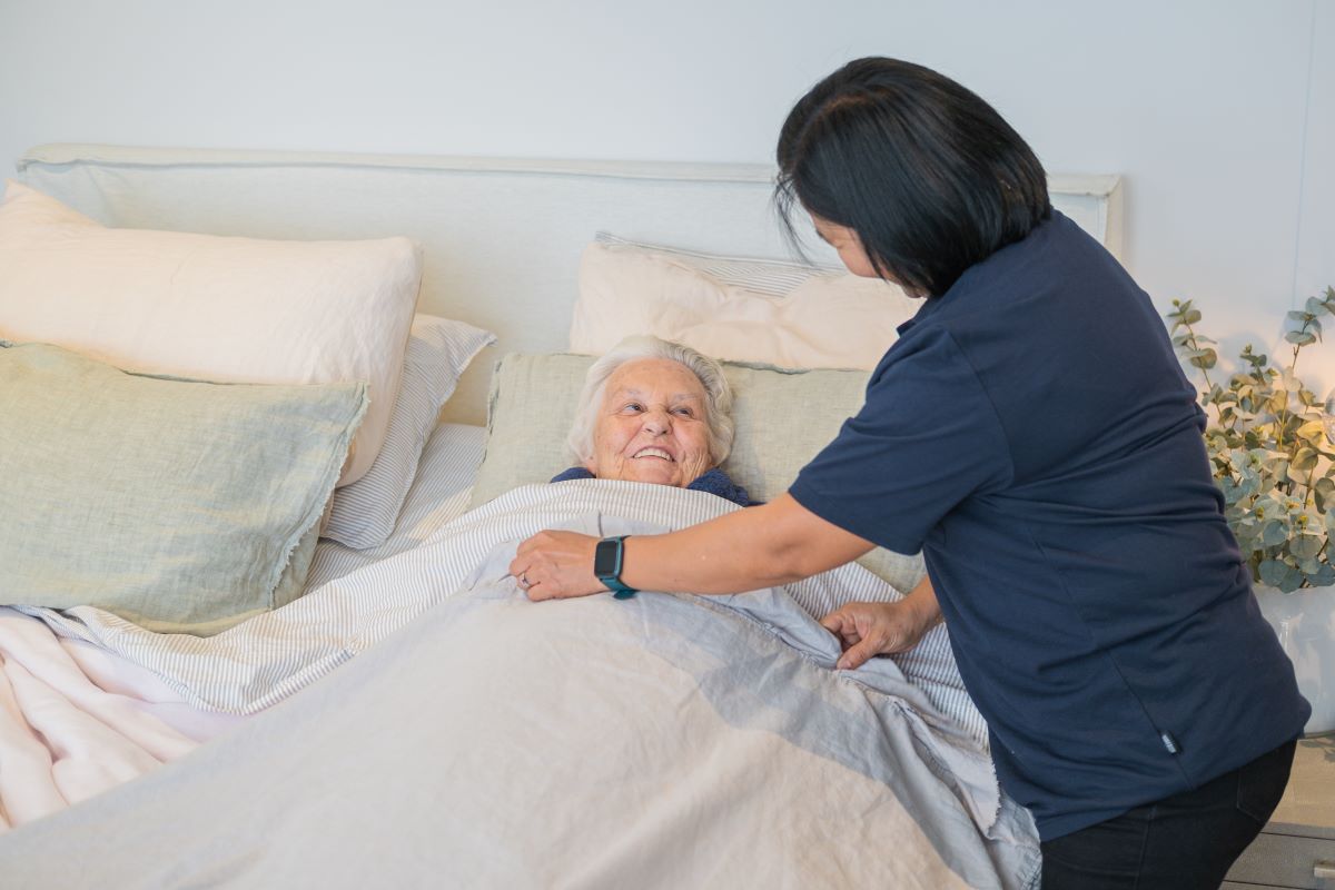 A support worker helps an elderly woman with her nighttime routine.