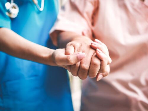 A nurse's hand holds the hand of a patient.